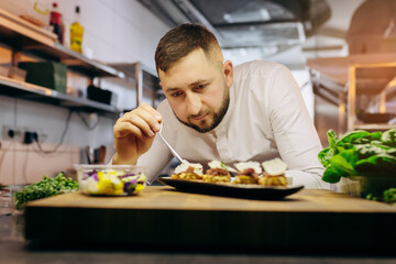 Chief chef serving snacks, canapes or sandviches adding finishing touch on dish before it is going to be served for restaurant guests