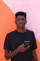Young man with curly hair looking at camera using smartphone