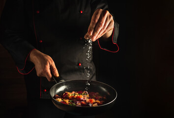 Professional chef adds salt to a steaming hot pan. Menu idea for a hotel with advertising space. Asian cuisine