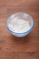 Confectionery flour in a bowl on a wooden table.