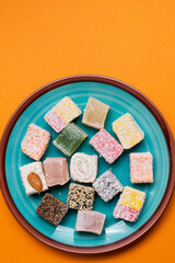 sweets in the form of squares with nuts lie on a blue plate on an orange background