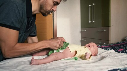 Caring father changing reusable diaper on infant baby at home. Modern eco friendly cloth nappy for infant child hygiene. Sustainable lifestyle, zero waste concept.