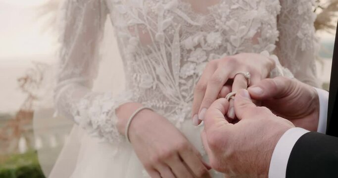 Groom puts marriage ring on bride finger at wedding ceremony