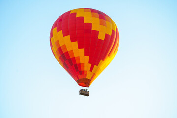 Fototapeta premium Colorful balloon flying over a clear blue sky during a sunset on a sunny day in Cappadocia, Turkey, copy space