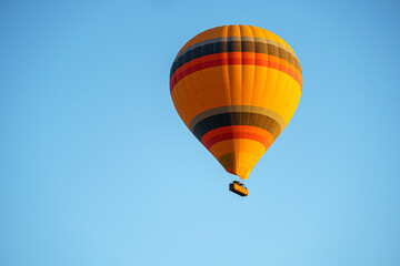 Colorful balloon flying over a clear blue sky during a sunset on a sunny day in Cappadocia, Turkey, copy space