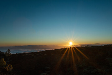 Beautiful sunset over the volcanic landscape and nature up in the mountain. Golden hour and sunlight above the clouds.  Photo taken at Teide national park in Tenerife, Spain.