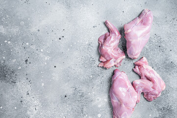 Raw rabbit legs slices on a butcher board. Gray background. Top view. Copy space