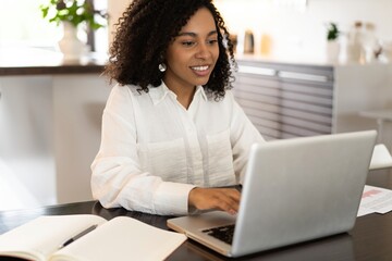 Confident african american businesswoman working on laptop at her workplace at modern home.