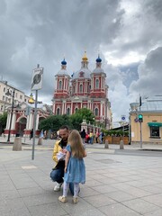 A young father walks with his daughter around the city. A man holds a child by the hand. walk to the red-white church with golden domes. Children and religion, church education of children.