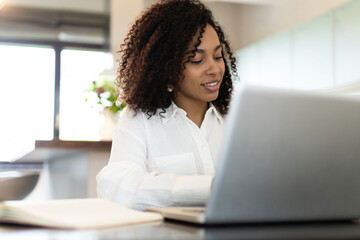 Confident african american businesswoman working on laptop at her workplace at modern home.