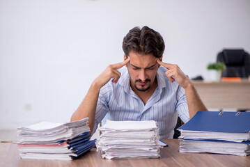 Young male employee and too much work in the office