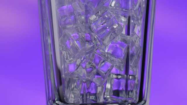 The glass with ice rotates on a purple background, the camera movement is directed from the bottom up