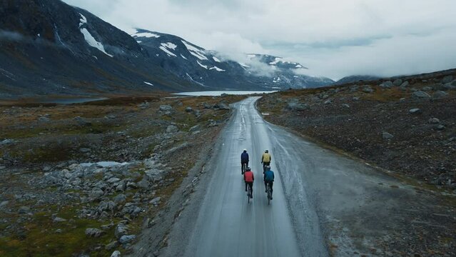 Professional road cyclist on fast and light carbon bicycle descends mountain road in Norway. Fit, athletic team, friends group on recreational daily ride trip, training camp, enjoy time outdoors