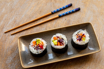 Vegan Futomaki (thick sushi rolls) with zucchini, celery stalks, carrot, red cabbage and red bell pepper vegetables.