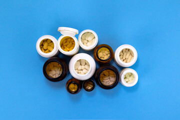 Opened drug bottles on blue background on blue background. Medical treatment and pharmaceutical concept.