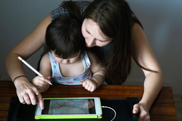 Mother with her daughter drawing on digital drawing tablet