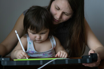 Mother with her daughter drawing on digital drawing tablet