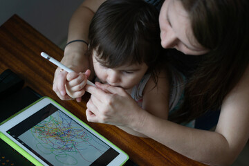 Mother with her daughter drawing on digital drawing tablet