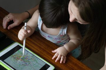 Mother with her daughter drawing on digital drawing tablet