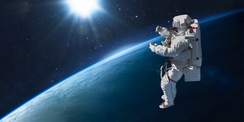 Astronaut in outer space on orbit of Earth planet. Sky and clouds. Spacewalk with stars. Sun light on background. Elements of this image furnished by NASA