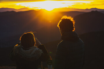 pareja tomando fotos del atardecer en la montaña