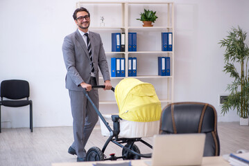 Young male employee looking after new born at workplace