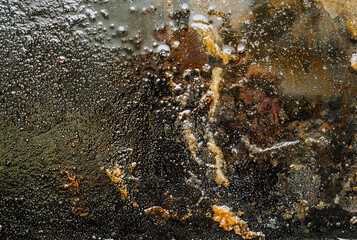 Texture, background, top view of a black tray smeared in fat, oil, after cooking a meat dish. Food photography, abstract.