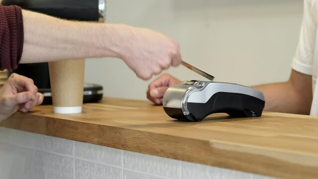 Close-Up Of A Man's Hand Holding A Credit Card On A Banking Device For Accepting Payments Online in A Cafe