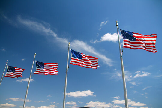 Four United States flags waving in the blue sky