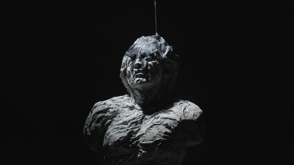 A white statue of a man. A close-up shot on a black background.