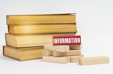 On a white surface, a stack of books and wooden blocks, on a red block there is an inscription - Information