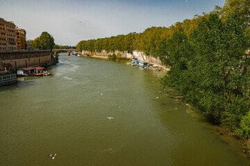 Beautiful view of the Tiber River and the bridge. Green slats along the coast protect from the sun.