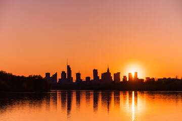Fototapeta na wymiar Big city skyline sunny evening in big city of Warsaw, Poland. High buildings skyscrapers on horizon over Wisla river surface. Sunset, downtown beautiful cityscape panorama lit with warm sun light