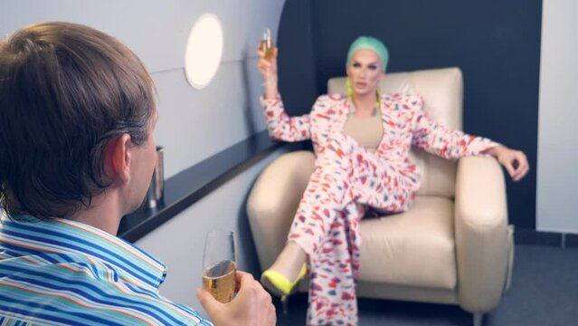 a respectable man and a guy in women's clothes, with makeup and a blue wig, drink champagne in a VIP plane.