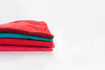 Stack of folded clothes, clean red cotton textile t-shirts on white background with copy space. Laundry, washing, ironing concept