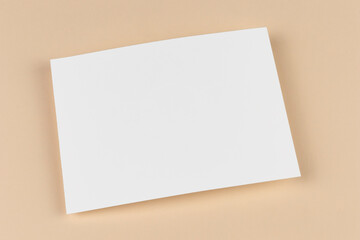 An empty blank sheet of paper on beige background. Template and mock up for invitation, letter, card, document, business design, cover and reminder. Simple minimalistic design.