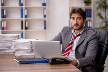 Young male employee unhappy with excessive work in the office