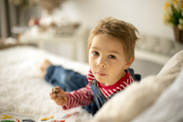 Naklejka premium Cute child at home with little newborn chicks, eating chocolate candy in bed