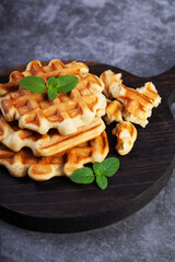 Homemade freshly baked belgian waffles with mint leaves on dark background. - 501011117