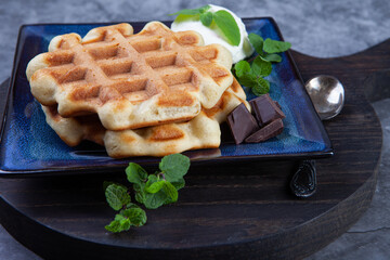 Homemade freshly baked belgian waffles with mint leaves on dark background. - 501011119