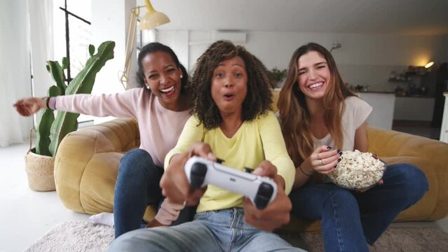 Three women having fun playing video games at home - Teenagers addicted to trendy technology 