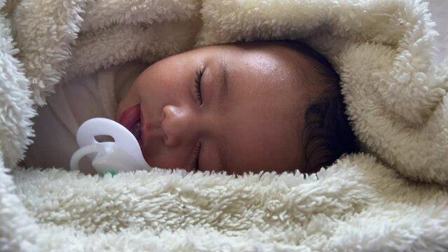Sweet peaceful baby lying on a white bedsheet enjoy daytime nap