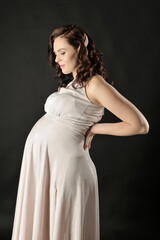 Beautiful pregnant woman in the dress posing isolated on the black