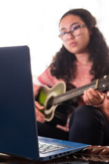 Teen learning to play guitar with a laptop