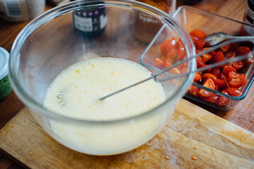 Process of making homemade omelet with cheese and tomatoes.