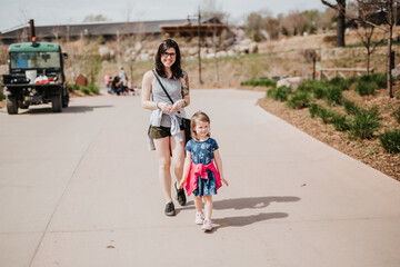 Mother and daughter walk along sidewalk at zoo on Summer Day