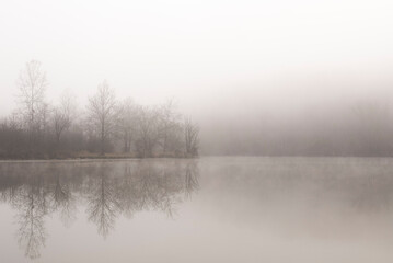 Foggy morning along the water with reflection of trees at Bald E