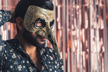 mediumportrait of a Latin man in a golden venicean mask on pink isolated background, copyspace....
