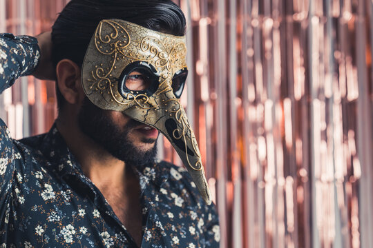mediumportrait of a Latin man in a golden venicean mask on pink isolated background, copyspace. High quality photo