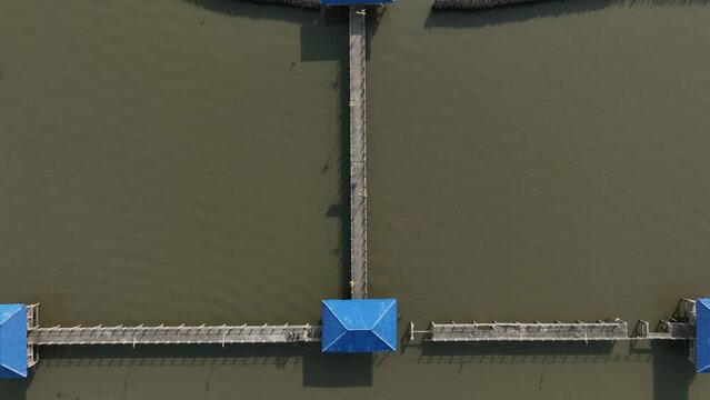Aerial view of old small house with a slightly broken bridge in the shore line of Thailand
